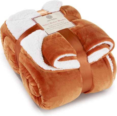 Reversible throw blanket with one side burnt orange and the other side crisp white, folded on a bed for a warm fall accent