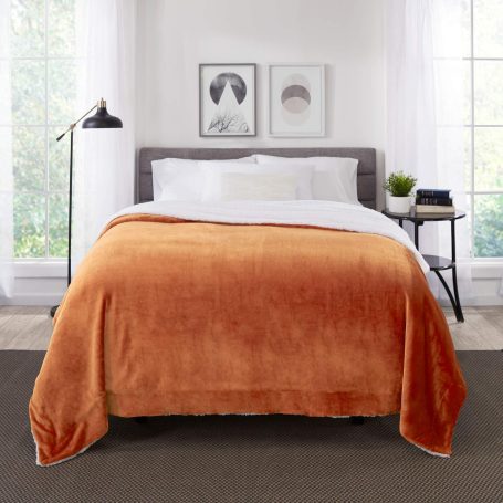 Reversible throw blanket with one side burnt orange and the other side crisp white, on a bed for a warm fall accent